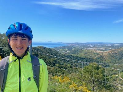 Young cyclist overlooking green landscape, the seashore and blue sky