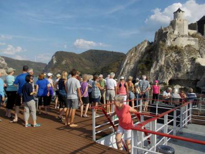 danube ship with passengers on the sundeck passing the fortress Golubac on the way to the iron gate