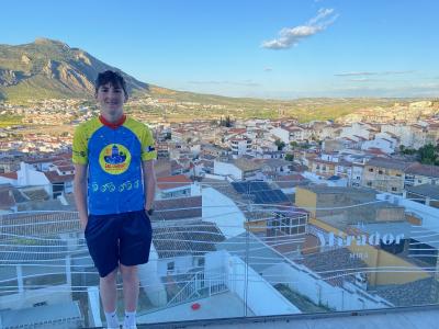 Young cyclist overlooking the village with mountains and blue sky