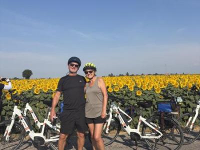Happy cyclists standing in front of a field full of sunflowers and a blue sky