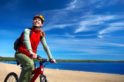 Young smiling woman cycling near the lake 