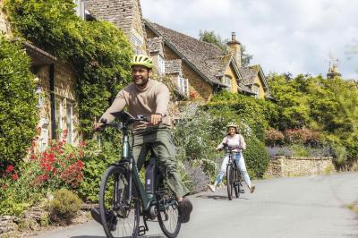 Radfahrer in Dorf in Cotswolds